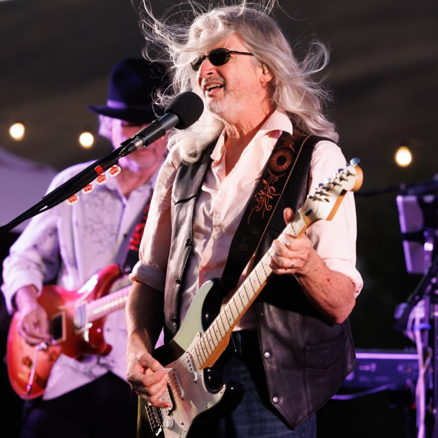 Performer singer with guitar and grey hair flying in air