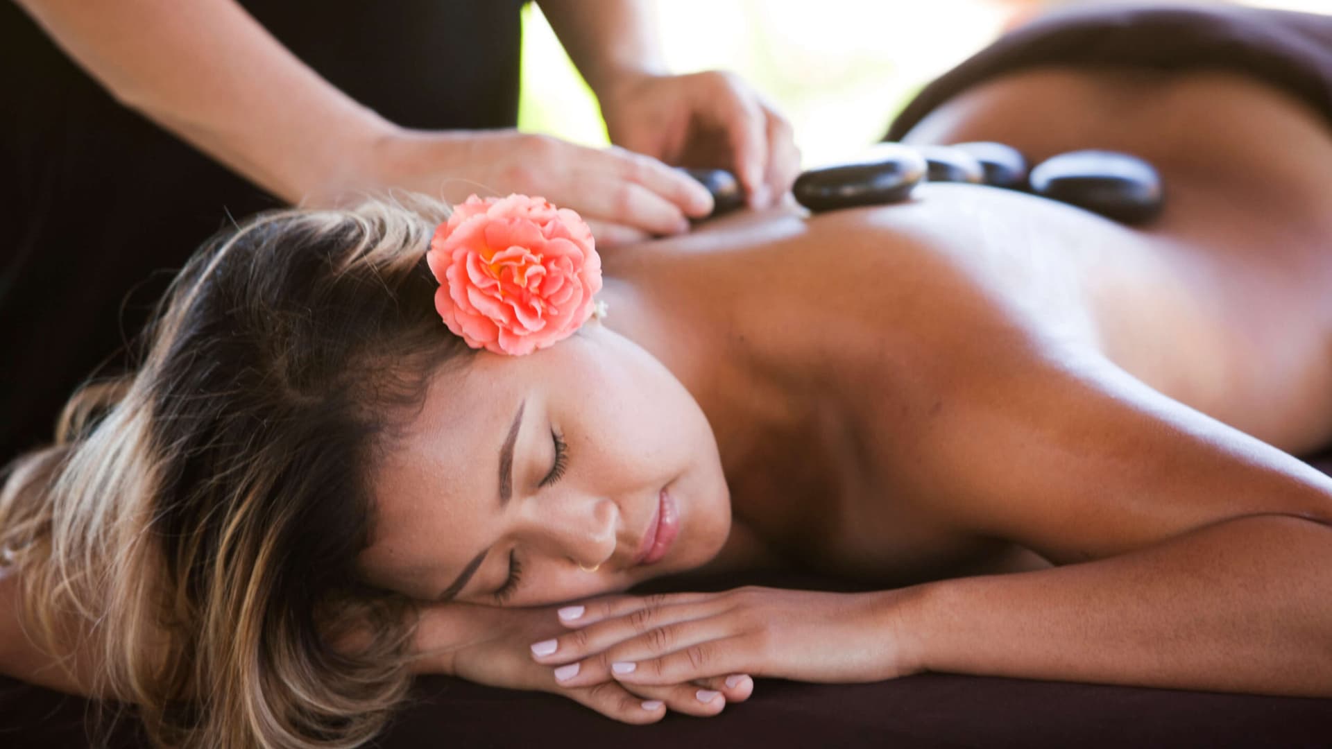 A woman laying face down on a massage table getting a hot stone massage.