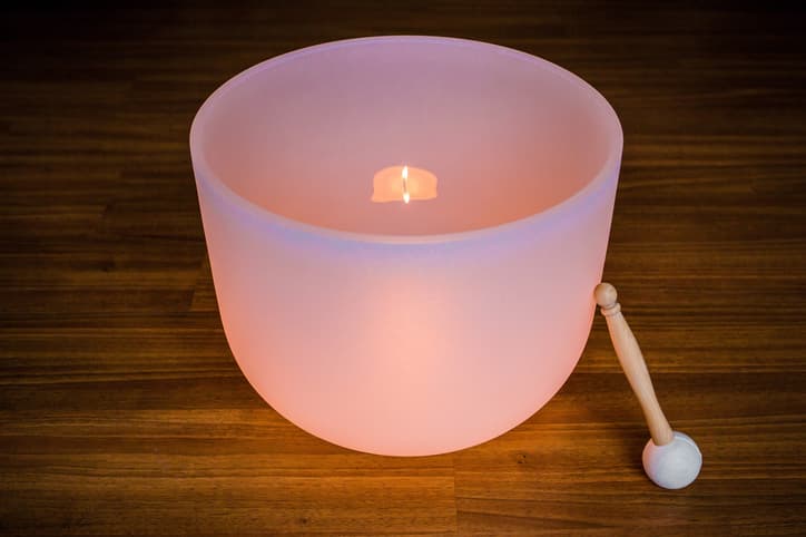 A glowing crystal singing bowl with a wooden mallet beside it.