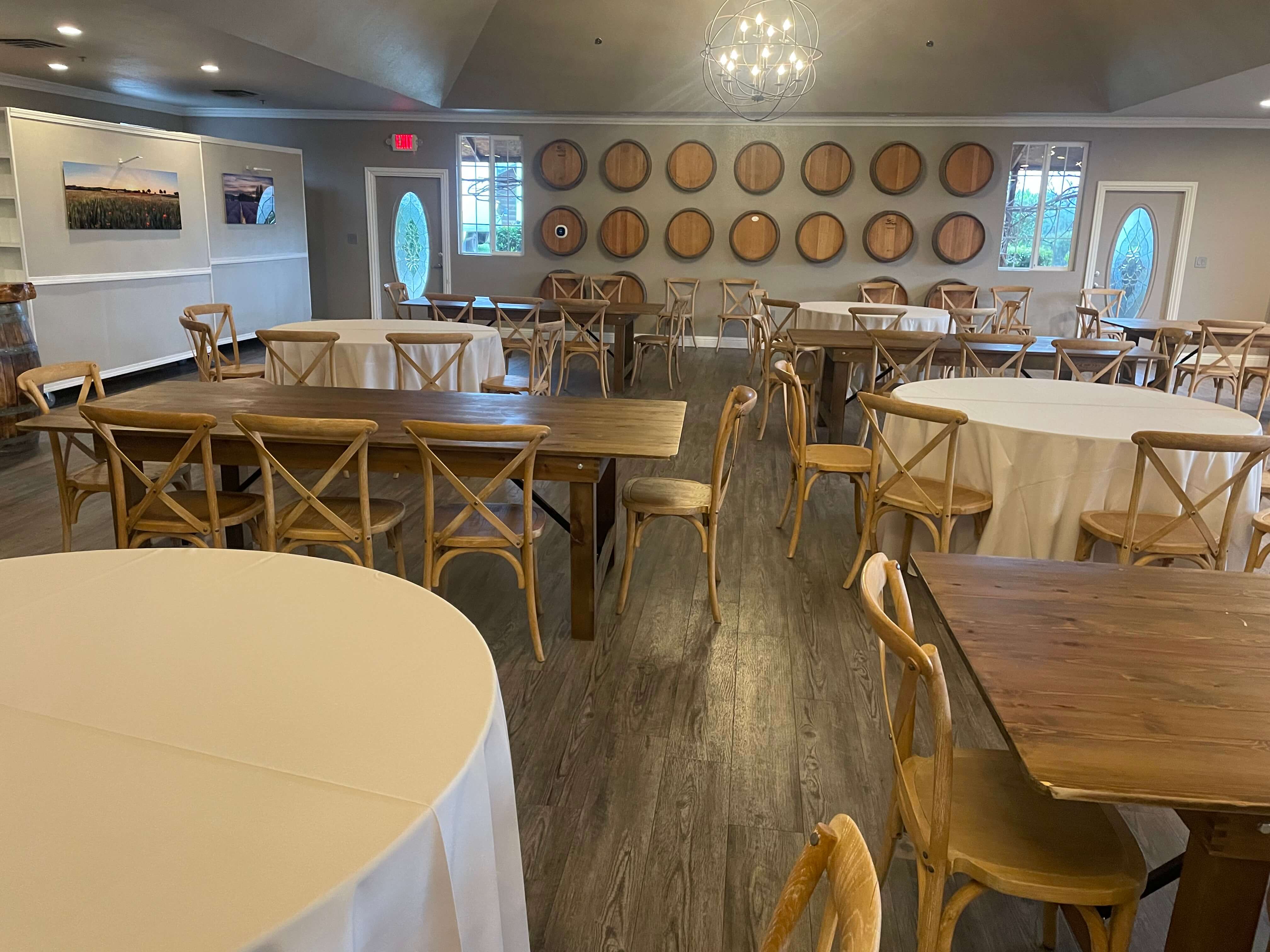 A spacious banquet room with wooden tables, chairs, and wine barrels decor.