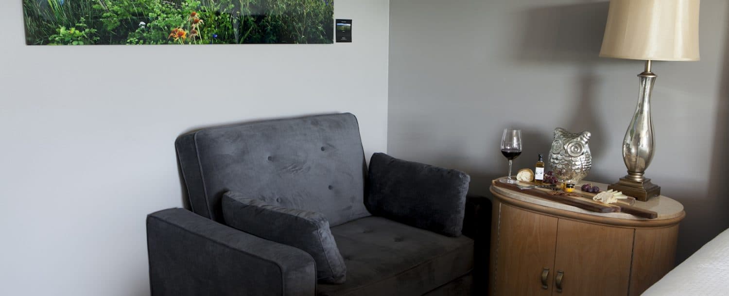 A comfortable gray armchair offers a relaxing spot to unwind with a glass of wine and a good book.