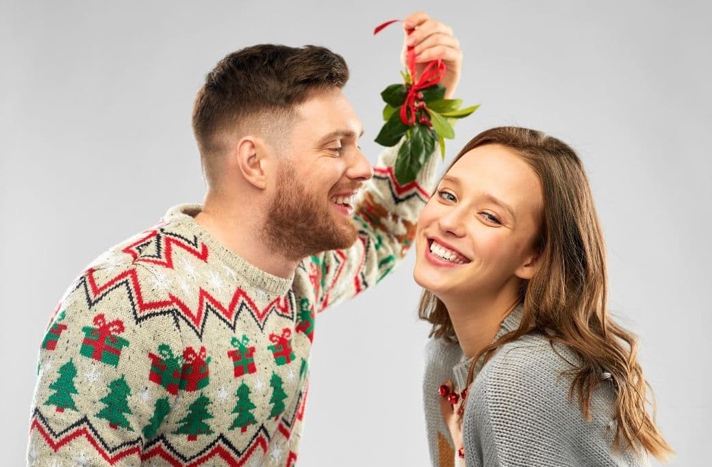 couple leaning in for kiss under mistletoe couple leaning in for kiss under mistletoe
