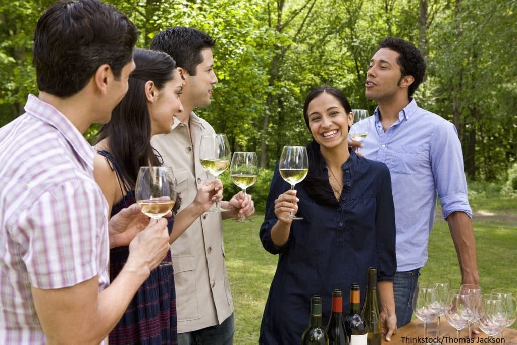 a group of people smiling and talking holding glasses of white wine a group of people smiling and talking holding glasses of white wine